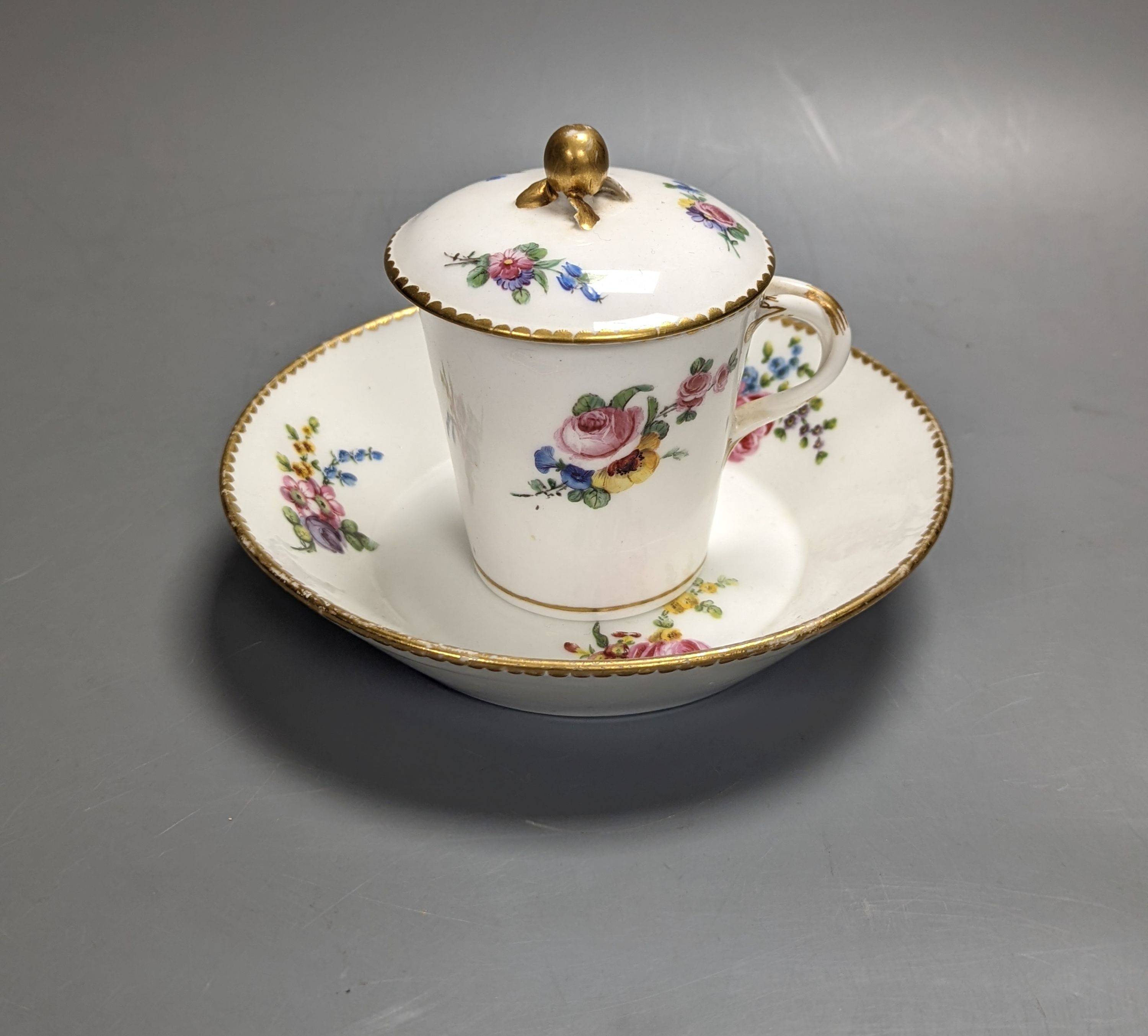 A Sevres tapering cup with entwined handle and cover and stand painted with flowers, date code for 1780, painters mark for Le Bel jnr., square incised marks, height 10.5cm